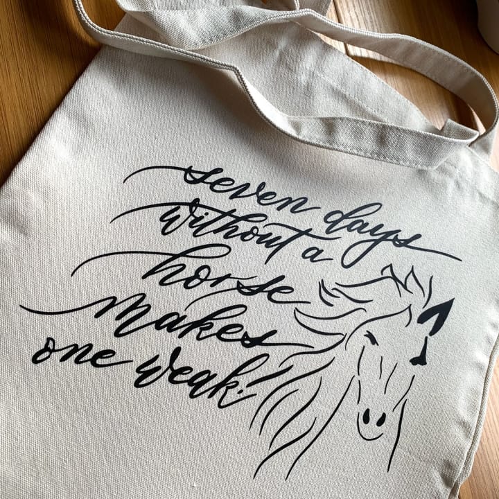 Close-up of hand-lettered script and a horse illustration on a canvas tote bag