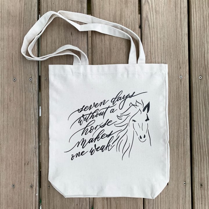 Canvas tote bag hand-lettered 'Seven days without a horse makes one weak' beside a horse illustration