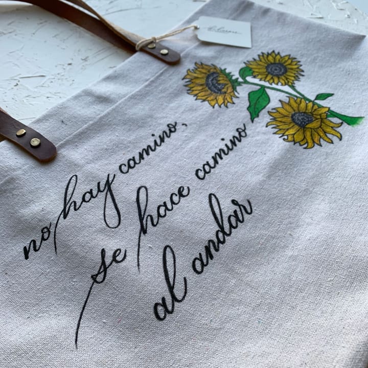 Close-up of hand-lettered script and painted sunflowers on a canvas tote bag