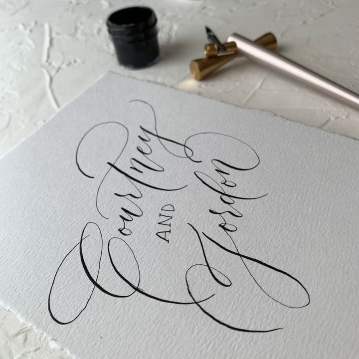 Hand lettering in progress on an envelope, pointed pen and ink visible