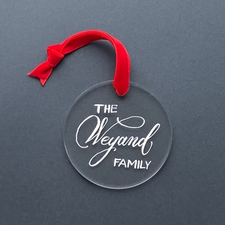 Clear acrylic ornament hand-lettered The Weyand Family with a red ribbon