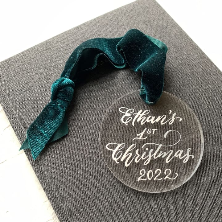 Clear acrylic ornament hand-lettered with a baby's first Christmas