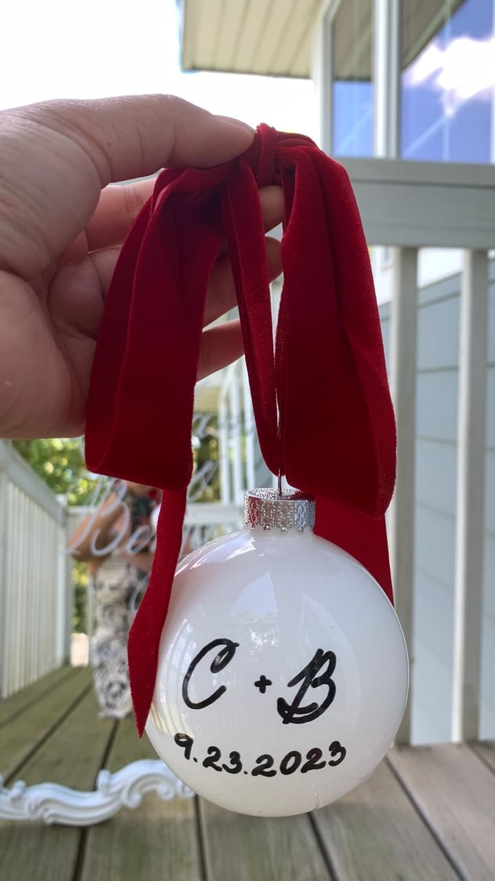 White glass ornament hand-lettered with a couple's initials and wedding date