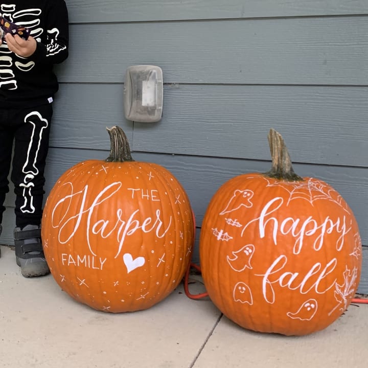 Two hand-lettered pumpkins on a porch