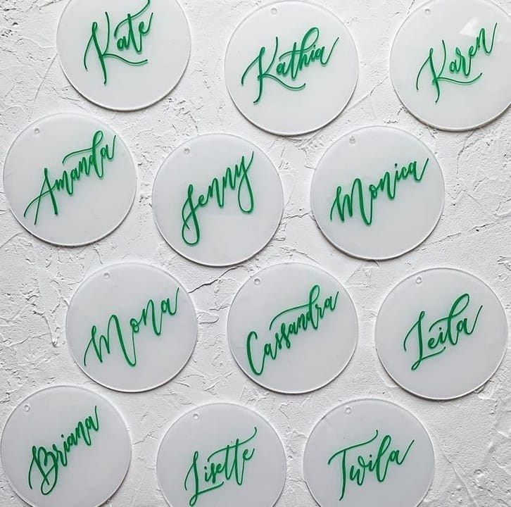 Round frosted acrylic name tags hand-lettered in bright green ink