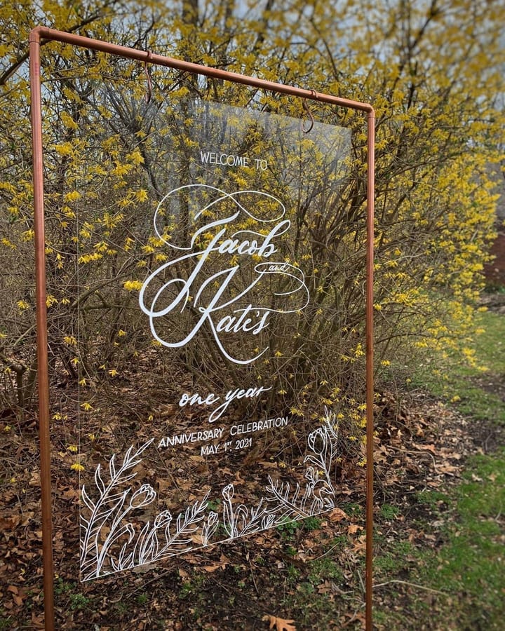 Hand-lettered welcome sign for an anniversary celebration in a copper stand