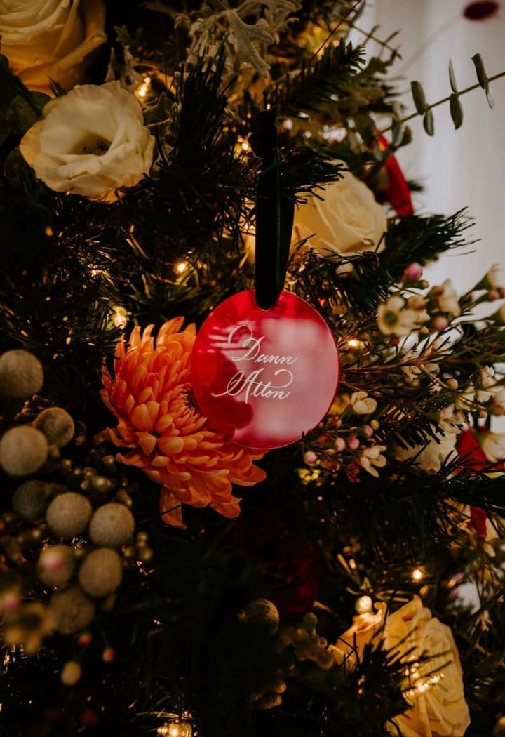 Close-up of a red acrylic escort card ornament hand-lettered in white ink