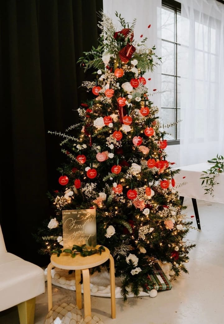 Escort card ornaments hanging on a flower-trimmed Christmas tree