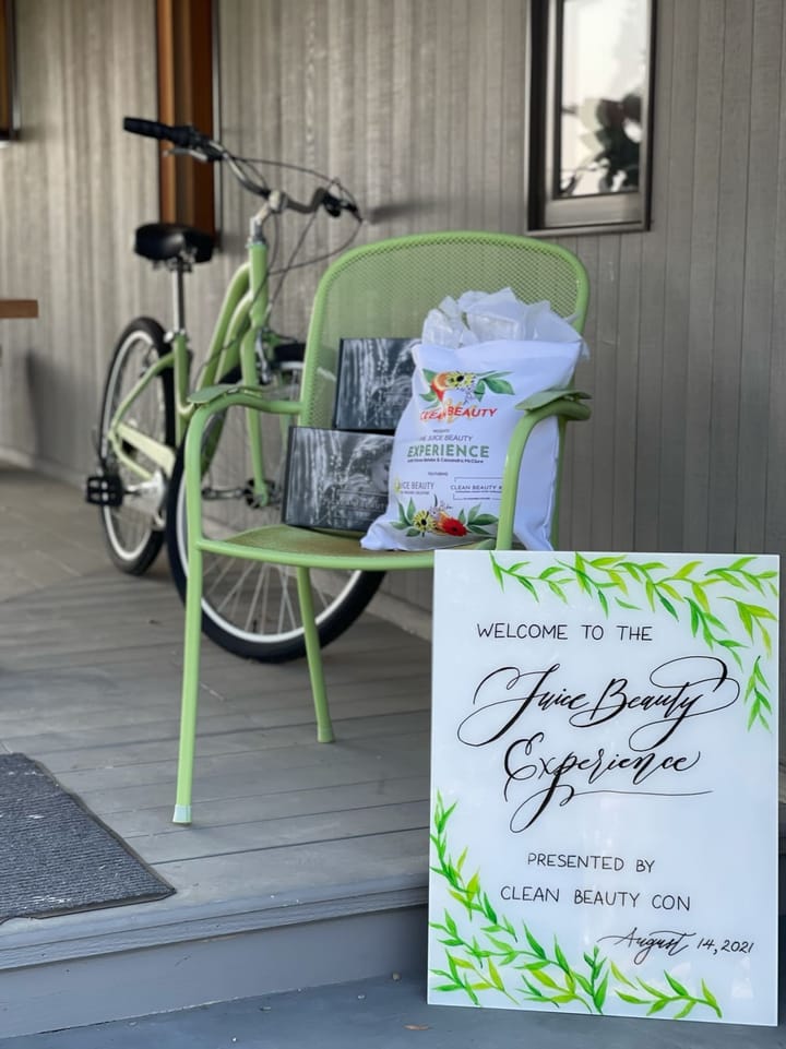 Hand-lettered event sign with a painted greenery border