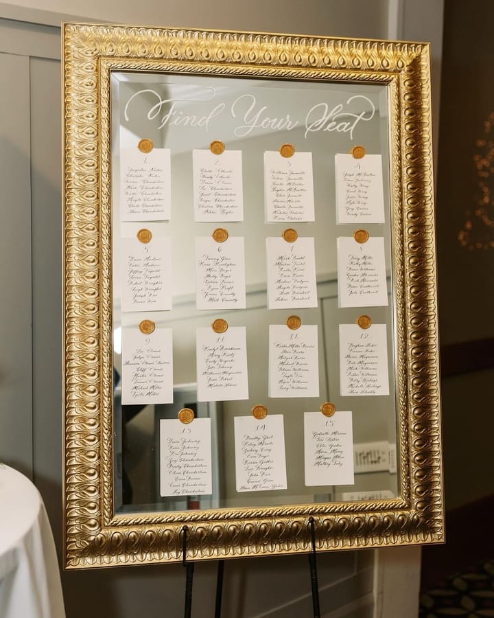 Find Your Seat mirror seating chart in an ornate gold frame with wax-sealed table cards